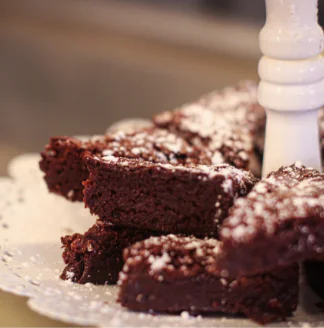 Chocolate cake on a plate with powdered sugar.