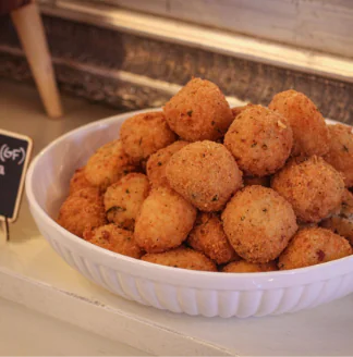 A bowl of fried balls sitting on a counter.